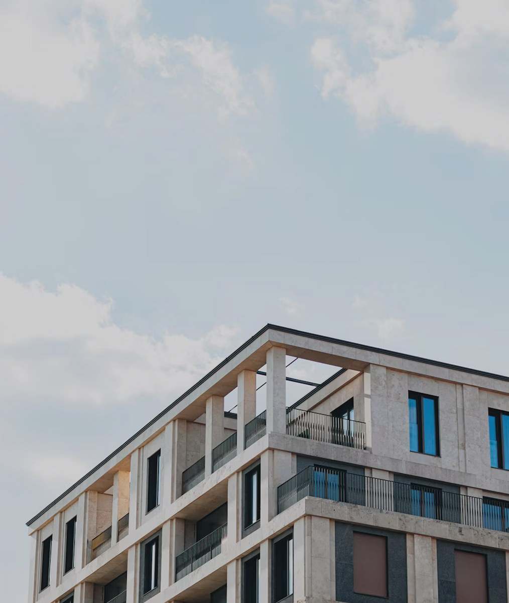 Modern limestone apartment building with balconies against a pale sky